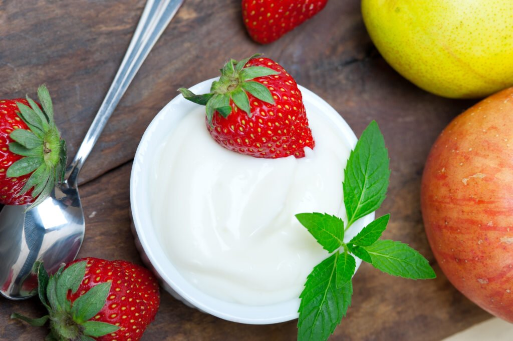 fresh fruits and whole milk yogurt on a rustic wood table