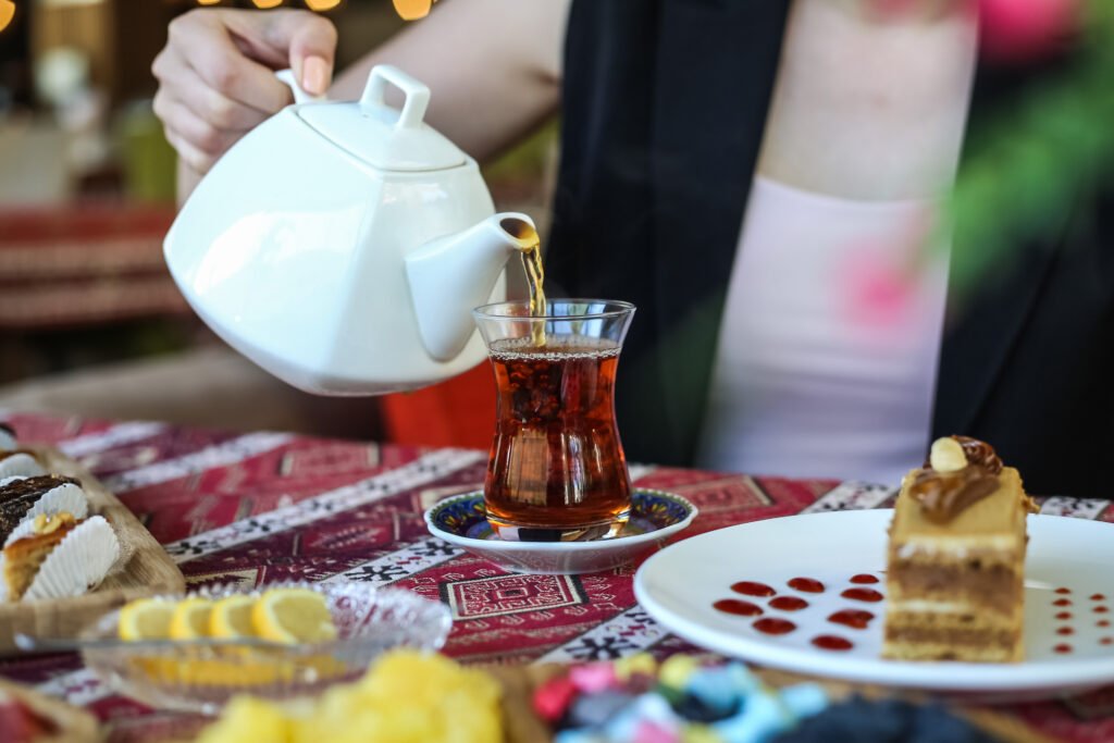 side view a woman pours tea in armudu glass 